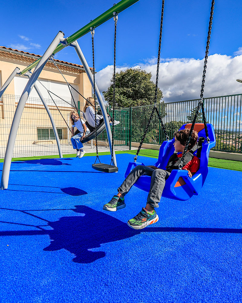 Un grande telaio per altalene con diversi tipi di sedili per altalene, su cui i bambini si dondolano.